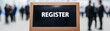 © KENZOGROW - Register now for enrollment. Sign indicating a registration area with blurred figures in the background.