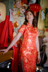 A woman in a red dress stands in front of a table with a sign on it. She is smiling and looking at the camera