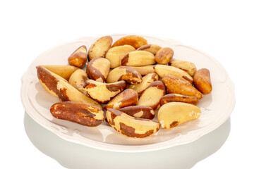 Wall Mural - Brazil nuts without shells on a white ceramic plate, close-up, isolated on a white background.