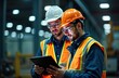 © Maryna - Two engineers in safety gear examine digital tablet. Work in factory. Industrial setting. Review data for tech support. Team analysis. Consult. Pro tech team. Manufacturing plant. Heavy machinery.