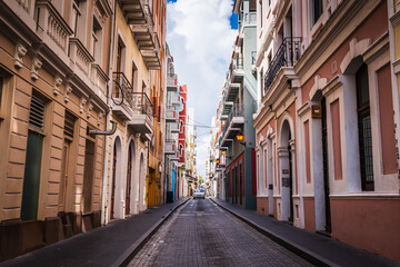 A car bears down on the narrow cobblestone colorful Calle Tetuan street in Old San Juan.