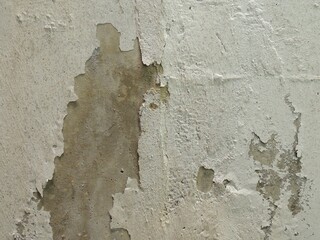 cement surface with a fragment of fallen plaster, part of an old dilapidated building macro background of old cracked texture of gray-white shade, a piece of concrete wall with fallen off whitewash