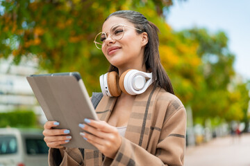 Wall Mural - Young pretty woman at outdoors holding a tablet