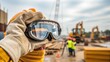 © DigitalSpace - Closeup of a hand adjusting protective goggles before starting a task signifying personal responsibility in adhering to safety protocols amid the busy construction environment.