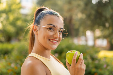 Wall Mural - Young pretty woman with an apple at outdoors smiling a lot