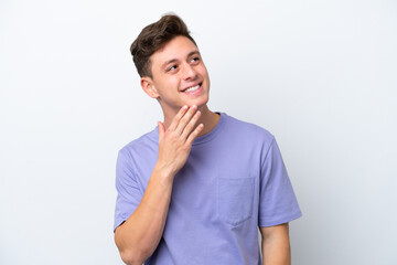 Wall Mural - Young handsome Brazilian man isolated on white background looking up while smiling