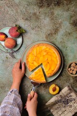 Wall Mural - Summer pie on shortcrust pastry with custard, fresh peach slices and jelly on a green ceramic plate on a green concrete background.