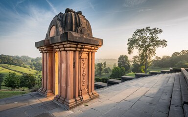 Wall Mural - Sunrise illuminates ancient stone shrine atop hill overlooking valley.