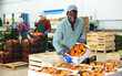 © JackF - Positive african-american man working in vegetable factory, carrying crate full of ripe tomatoes.