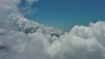Wall Mural - flying through beautiful white fluffy clouds in blue sky. airplane travel background, 4k