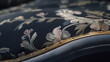 © Muhammad - A close-up shot of a luxurious velvet sofa in deep gray, featuring brass detailing along the edges and a silk cushion with embroidered patterns.