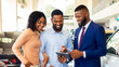 © Prostock-studio - Handsome Car Seller Showing Purchasing Details On Digital Tablet To Young Black Couple In Dealership Center, Happy African American Spouses Buying New Vehicle In Automobile Showroom, Closeup
