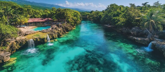 Wall Mural - turquoise river flowing through lush green landscape with waterfalls and a resort.