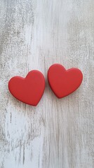 Poster - Two red wooden hearts lying on a light wooden background create a romantic atmosphere perfect for valentine's day, women's day, or any occasion celebrating love and affection