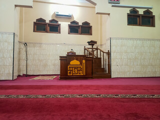 stunning interior shows the serene atmosphere of a small mosque. The wooden pulpit where the Islamic religious leader preaches is 