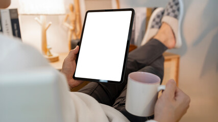 Wall Mural - man using tablet with blank screen for design mockup device, sitting in living room at home, work fr