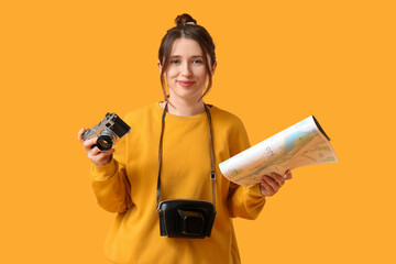 Wall Mural - Female traveler with photo camera and map on yellow background. Itinerary concept