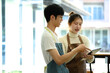 © Prathankarnpap - Coffee shop owners in aprons using digital tablet and discussing business plans