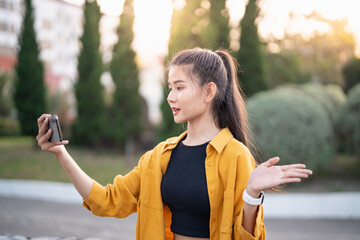 Wall Mural - Smiling young Asian woman using smartphone in urban city checking apps mobile outdoors