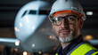 © kongkiat chairat - confident aviation engineer wearing hard hat and safety vest, standing in front of airplane