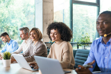 Wall Mural - Portrait of call center worker accompanied by her team. Smiling customer support operator at work.