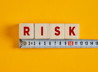 Measuring risk with wooden cubes and tape measure on yellow background