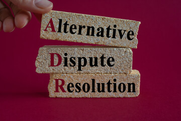 Wall Mural - Brick blocks with words Alternative Dispute Resolution on beautiful pink background. Businessman hand. Business concept.