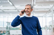 © Westend61 - Smiling mature businessman talking on smart phone in airport