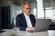© Westend61 - Businessman sitting and using laptop at office