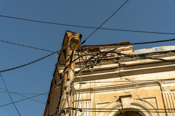 Wall Mural - A building with a lot of wires and a light on top. The wires are hanging from the roof and the building is old