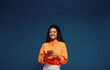 © Jacob Lund - Happy young woman texting in vibrant orange and blue colorblocking outfit