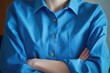 © Fotograf - A person wearing a blue shirt with their arms crossed, a common pose of contemplation or confidence