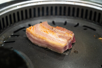 Wall Mural - Grilling pork meat on a iron BBQ board in Korean restaurant.