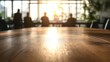 © Rizvan - Conference table in foreground with blurred silhouettes of attendees against a backdrop of sunlight-filled modern office space