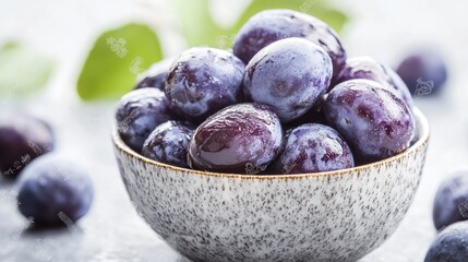 Poster - Bowl of Fresh Prunes on a Light Background with Green Leaves Showing Natural and Healthy Snack Option
