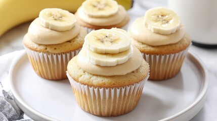 Aufkleber - Banana cupcakes decorated with creamy frosting and fresh banana slices on a white plate