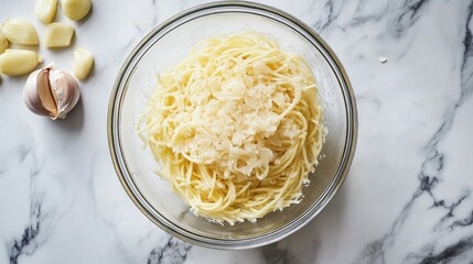 Poster - Bowl of uncooked pasta with sliced garlic cloves on a marble countertop ready for cooking preparation