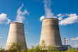 © Dmitry Naumov - Power plant infrastructure with cooling towers releasing steam on a sunny day
