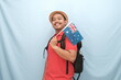 © Ahmad - A smiling traveler in a red shirt and straw hat, enthusiastically holding an Australian flag against a light blue background.