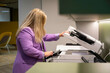 © Connect Images - A woman with long blonde hair, wearing a purple blazer, stands in an office making copies on a photocopier, Molenhoek, Netherlands
