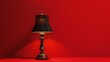 © Galib - A black lamp with a gold base is sitting on a red surface in front of a red wall.