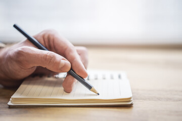 Poster - Close-up depiction of a man's hand taking notes in a notepad, with a blurred background