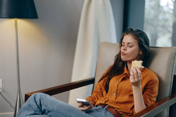 Canvas Print - Young woman relaxing at home, enjoying a healthy snack while watching TV, wearing casual clothing in a cozy living room atmosphere