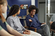 © Seventyfour - Portrait of African American woman as female counselor talking to teenagers during support group meeting in school