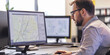 © plysuikvv - Man working at desk with computer monitors displaying maps