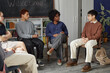 © Seventyfour - Full length shot of African American adult woman as female therapist working with teenagers sitting on chairs in circle during support group meeting