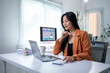 © Apichat - A woman is sitting at a desk with a laptop and a cup of coffee