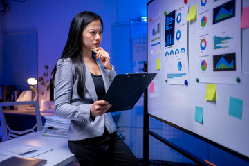 Wall Mural - A woman is sitting at a desk with a white board behind her