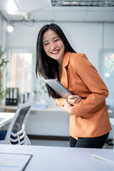 Wall Mural - A woman in an orange jacket is holding a tablet in her hand