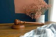 © zakiroff - Wooden gavel resting on judge's table with decorative flowers in vase symbolizing justice and law interior concept
